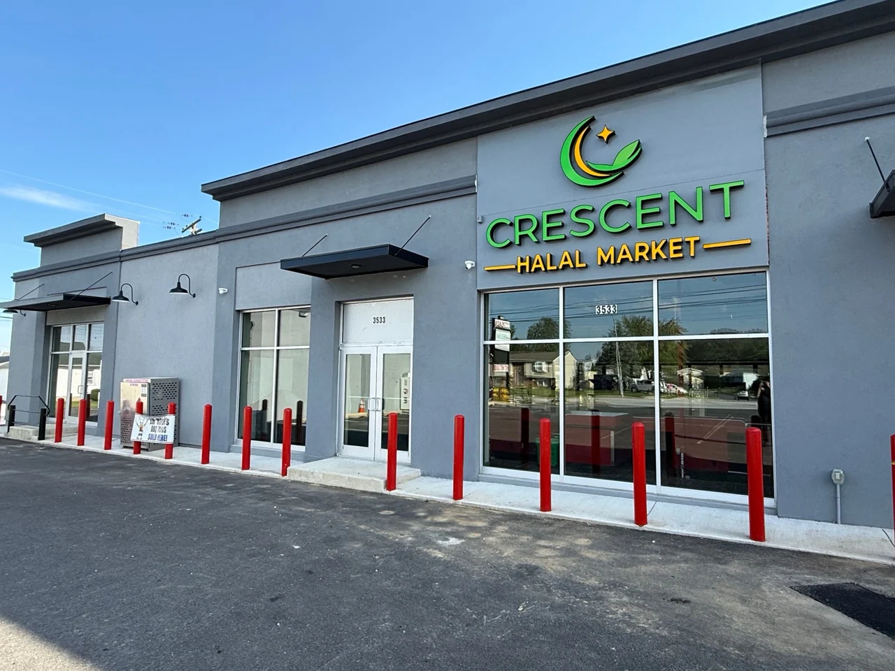 Crescent Halal Market’s gray storefront with its green crescent sign and glass entrance